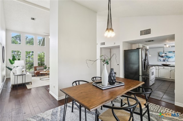 dining room with dark wood-style flooring, visible vents, and high vaulted ceiling