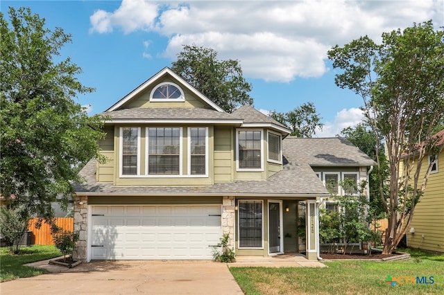 view of front of home featuring stone siding, a garage, fence, driveway, and roof with shingles
