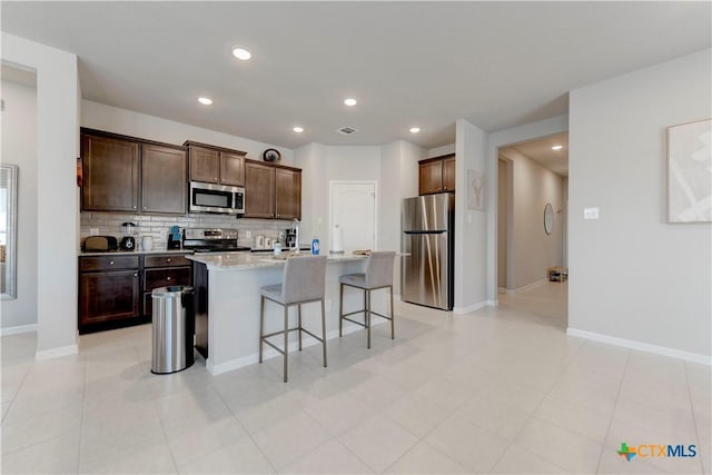3707 Mccleland Creek Trl, Temple, TX 76502 - kitchen featuring stainless steel appliances, tasteful backsplash, dark brown cabinetry, a breakfast bar, and an island with sink