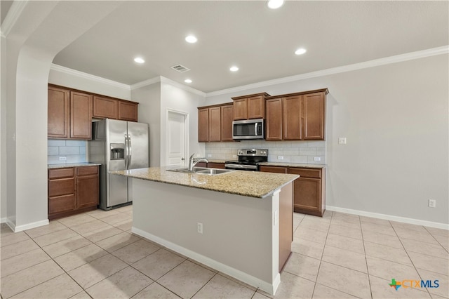 kitchen with light stone countertops, sink, an island with sink, light tile patterned floors, and appliances with stainless steel finishes