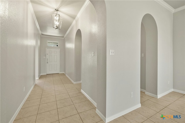 corridor featuring crown molding, light tile patterned flooring, and a notable chandelier