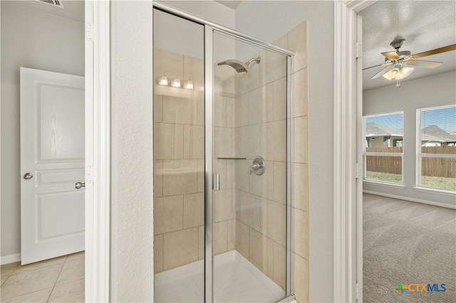 bathroom with a textured ceiling, a shower with door, tile patterned floors, and ceiling fan