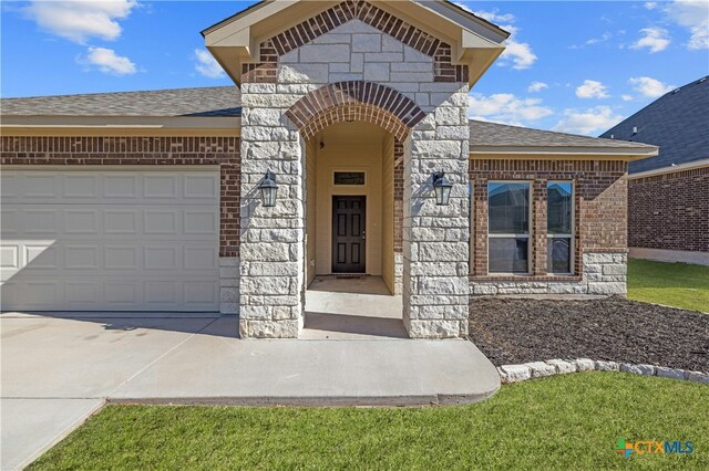 6109 Worthing Dr, Temple, TX 76502 - view of exterior entry with roof with shingles, a garage, brick siding, and concrete driveway