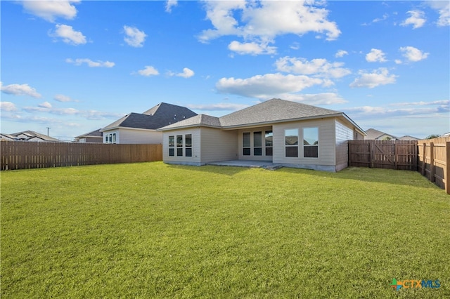 rear view of house featuring a lawn and a patio