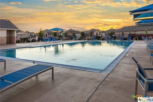 pool at dusk with a patio area