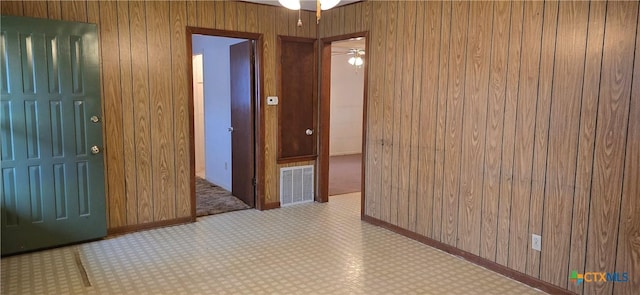 entrance foyer featuring ceiling fan and wooden walls