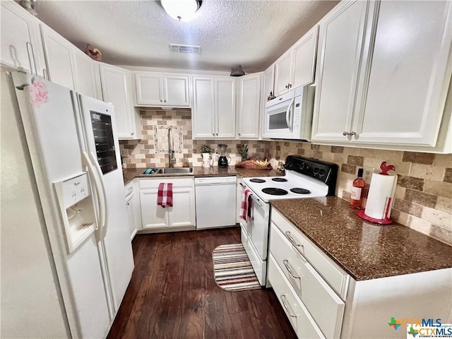 kitchen featuring sink, white cabinets, a textured ceiling, white appliances, and dark stone counters