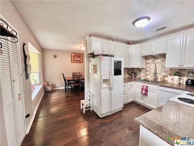 kitchen featuring white appliances, decorative backsplash, white cabinetry, dark stone countertops, and sink