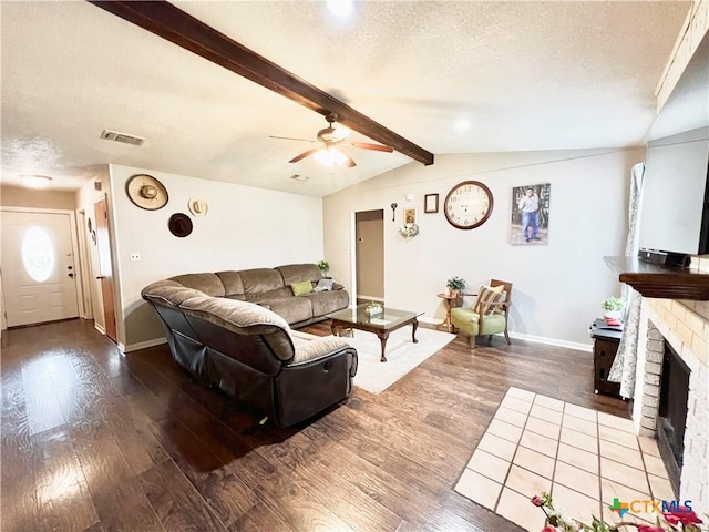 living room with a textured ceiling, a fireplace, ceiling fan, wood-type flooring, and vaulted ceiling with beams