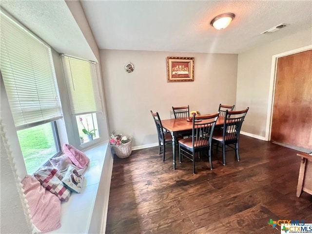 dining space with a textured ceiling and dark hardwood / wood-style floors