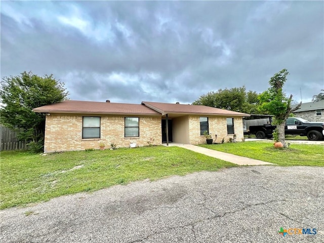 ranch-style home featuring a carport and a front yard