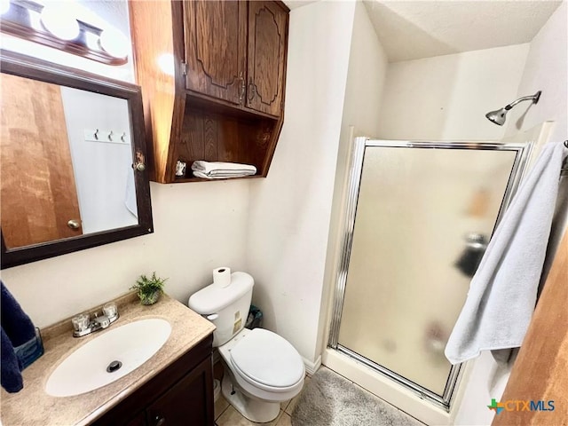 bathroom featuring vanity, a shower with shower door, and toilet