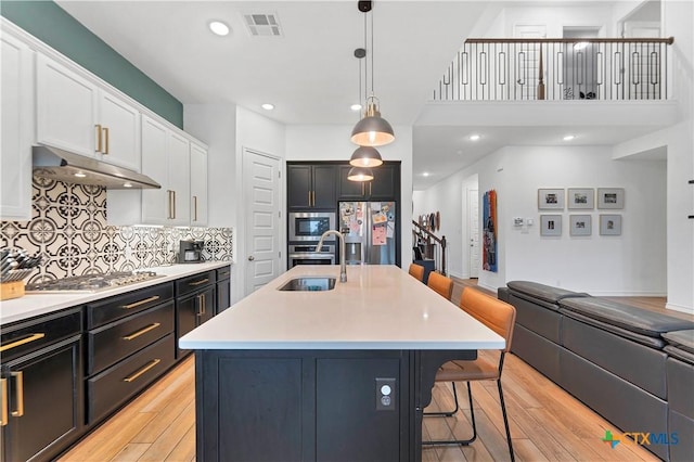 1620 Craftsman, New Braunfels, TX 78132 - kitchen with appliances with stainless steel finishes, under cabinet range hood, light wood-type flooring, a breakfast bar area, and open floor plan