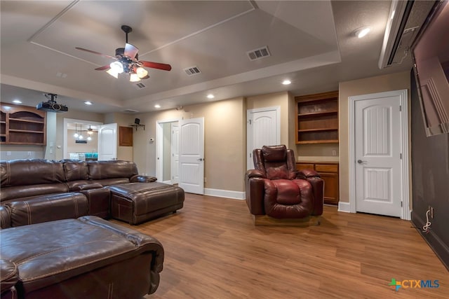 living room with a tray ceiling, ceiling fan, and light hardwood / wood-style floors