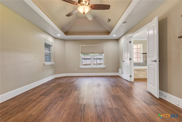 unfurnished bedroom with a tray ceiling, ceiling fan, dark wood-type flooring, and ornamental molding