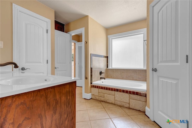 bathroom featuring tiled tub, tile patterned flooring, vanity, and a textured ceiling