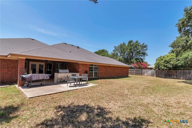 rear view of property with a lawn, an outdoor kitchen, and a patio area