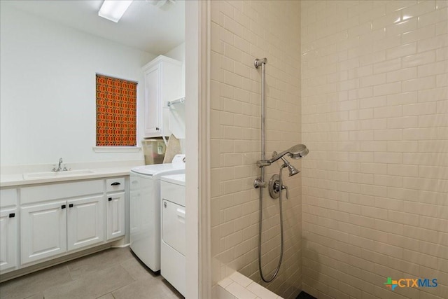 clothes washing area with a sink, light tile patterned floors, washing machine and dryer, and cabinet space