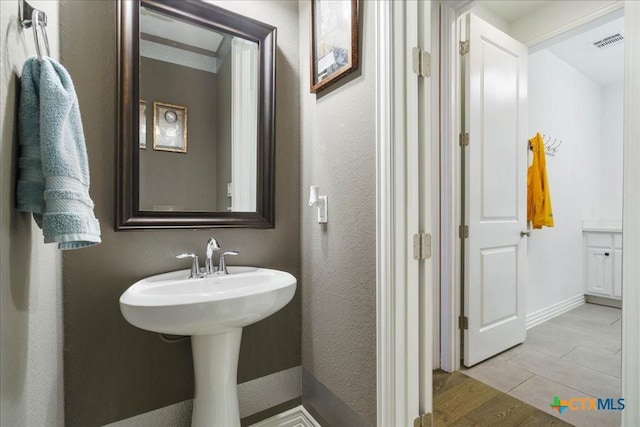 bathroom with a textured wall, visible vents, and wood finished floors