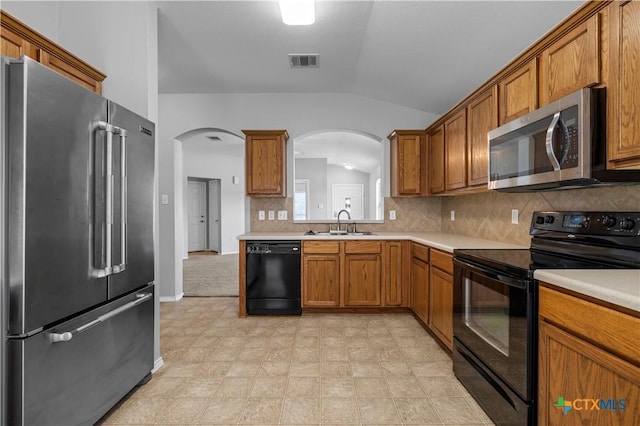 329 Big Timber Dr, Temple, TX 76502 - kitchen with black appliances, vaulted ceiling, arched walkways, brown cabinetry, and light countertops