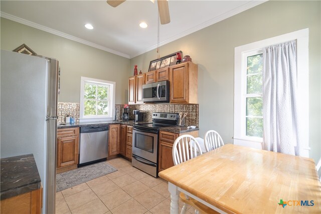 kitchen with stainless steel appliances, light tile patterned flooring, ornamental molding, ceiling fan, and decorative backsplash