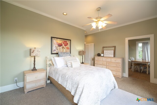 carpeted bedroom with ornamental molding and ceiling fan