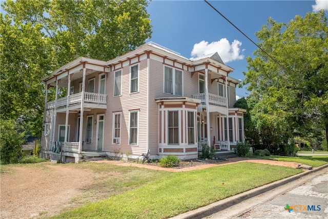 view of front of home featuring a front lawn, covered porch, and a balcony