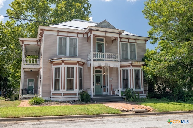 view of front of property featuring a front yard and a balcony