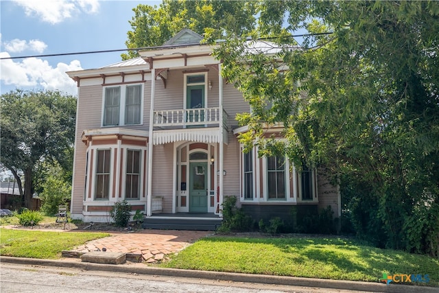 view of front facade with a front yard and a balcony