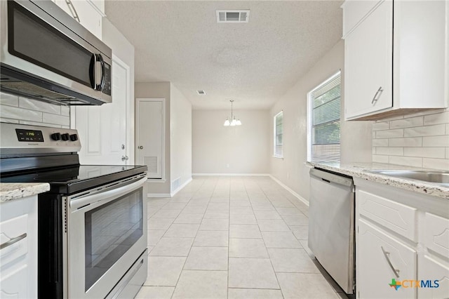 1008 Ronstan Dr, Killeen, TX 76542 - kitchen with stainless steel appliances, backsplash, a chandelier, baseboards, and white cabinets