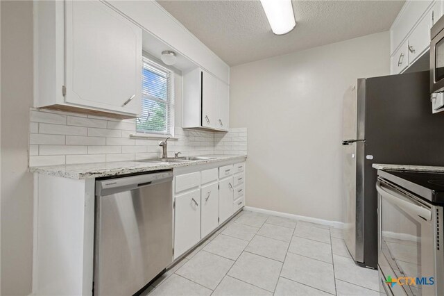 1008 Ronstan Dr, Killeen, TX 76542 - kitchen featuring appliances with stainless steel finishes, a sink, decorative backsplash, white cabinets, and a textured ceiling