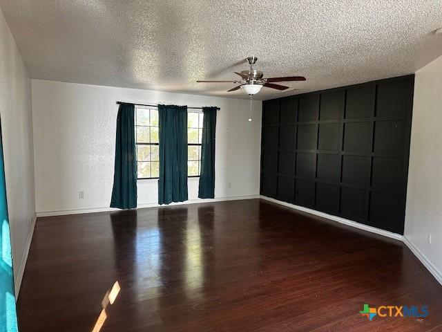 spare room featuring dark hardwood / wood-style flooring, a textured ceiling, and ceiling fan