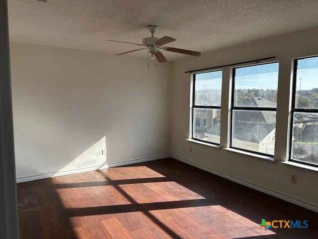 empty room featuring a textured ceiling, ceiling fan, and dark wood-type flooring