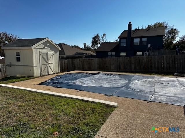 exterior space with a storage unit, a covered pool, and a patio area