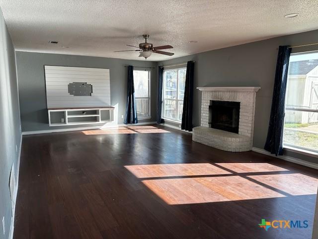 unfurnished living room with a textured ceiling, hardwood / wood-style flooring, a wealth of natural light, and ceiling fan