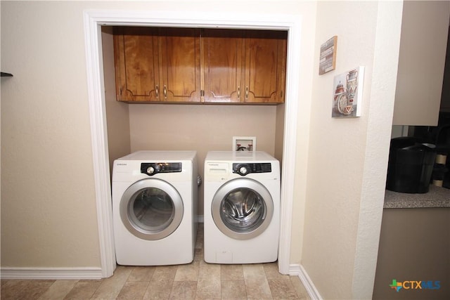 laundry area featuring baseboards, cabinet space, and washing machine and clothes dryer