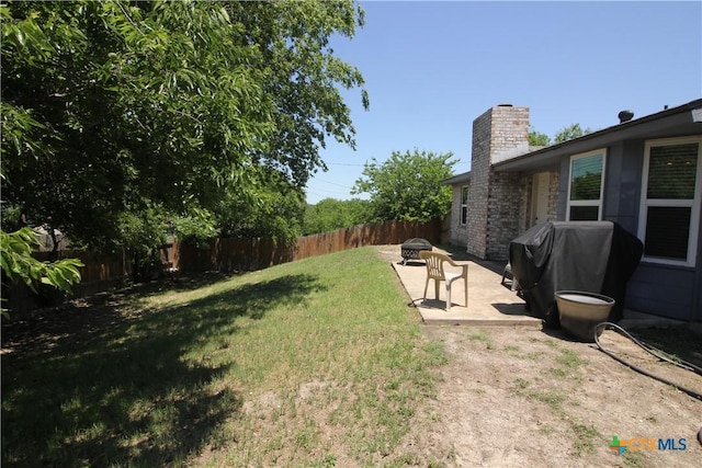 view of yard with a fenced backyard, a patio area, and an outdoor fire pit