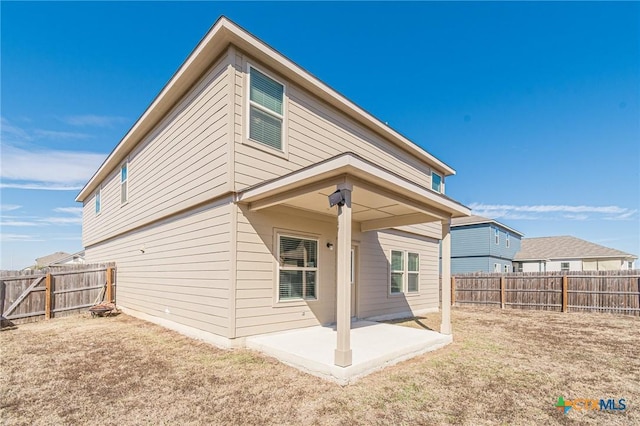 rear view of house featuring a fenced backyard, a yard, and a patio