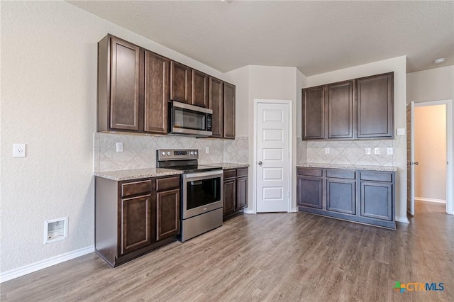 kitchen with stainless steel appliances, dark brown cabinetry, and light hardwood / wood-style flooring