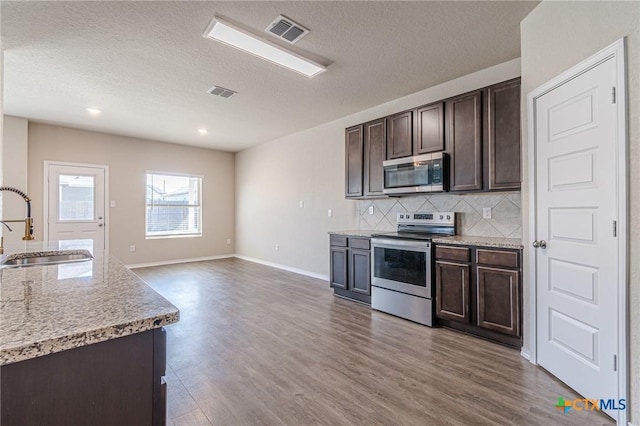 kitchen featuring dark brown cabinetry, sink, tasteful backsplash, a textured ceiling, and stainless steel appliances