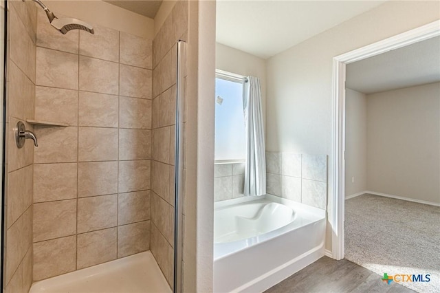 full bathroom with wood finished floors, baseboards, a garden tub, and a stall shower