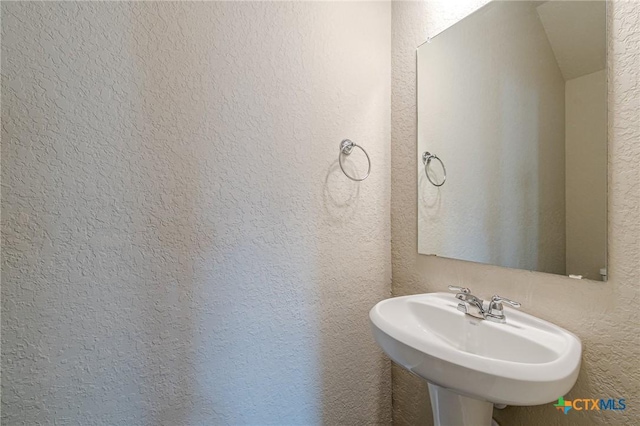 bathroom featuring a sink and a textured wall