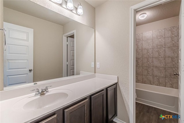 bathroom featuring hardwood / wood-style flooring, tiled shower / bath, and vanity