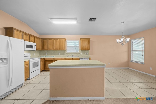 kitchen with light tile patterned floors, a kitchen island, white appliances, and an inviting chandelier