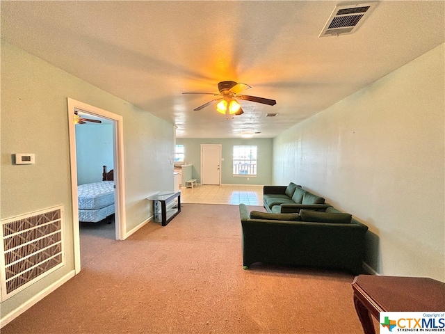 living room with a textured ceiling, light carpet, and ceiling fan