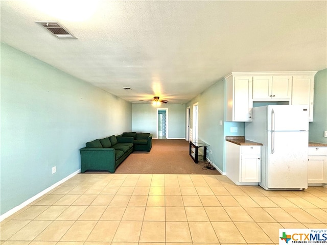 kitchen featuring ceiling fan, a textured ceiling, light tile patterned floors, white cabinets, and white refrigerator