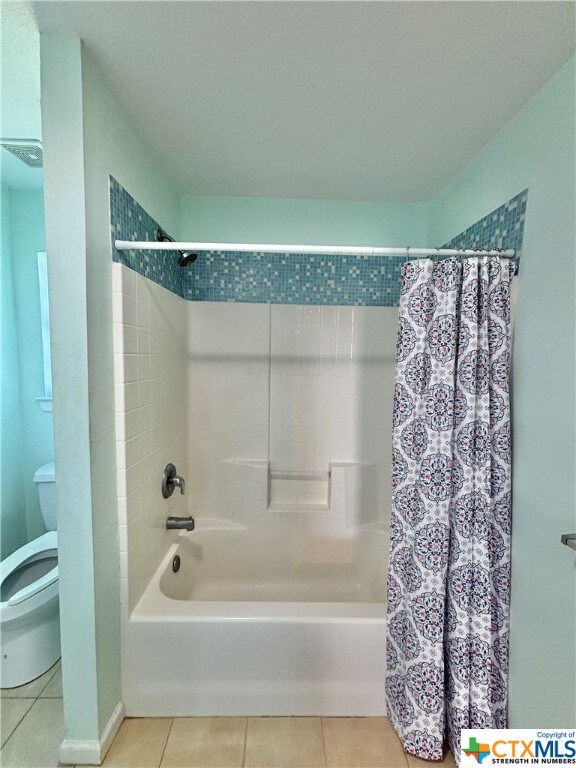 bathroom featuring toilet, shower / bath combo, and tile patterned flooring