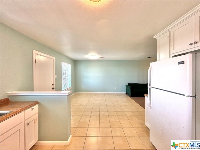 kitchen featuring white cabinetry, white refrigerator, a textured ceiling, and light tile patterned floors