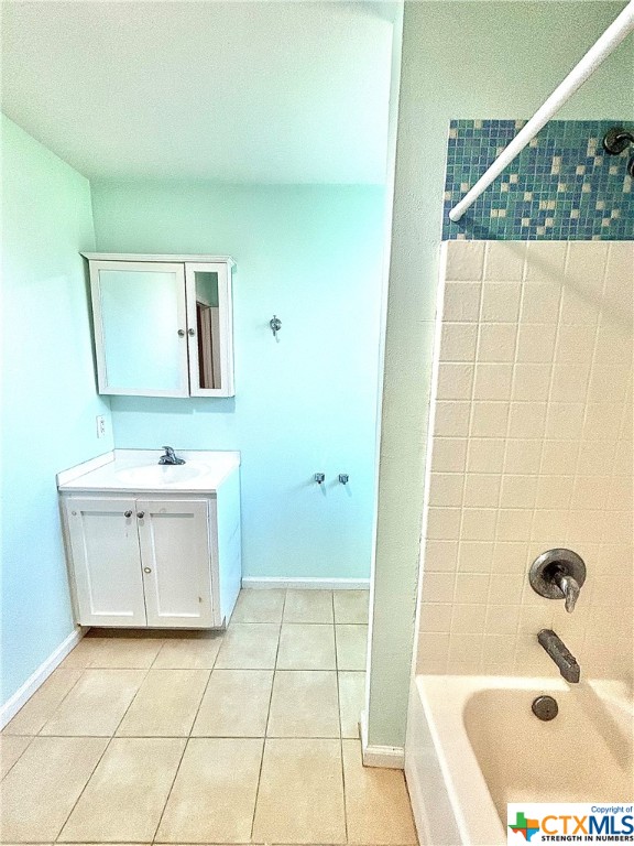 bathroom with tiled shower / bath combo, vanity, and tile patterned flooring