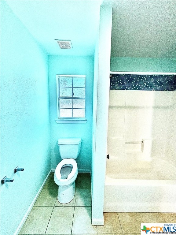 bathroom with tile patterned flooring, a tub, and toilet